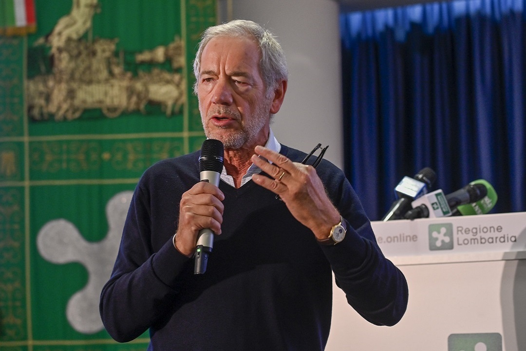 In foto Guido Bertolaso, assessore regionale al Welfare, mentre parla al microfono da un palco: la Lombardia partecipa al bando europeo per lo screening alla prostata tramite AI