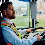 La foto ritrae un autista di autobus sulla cinquantina intento a manovrare il volante. Lo sguardo è rivolto sulla strada