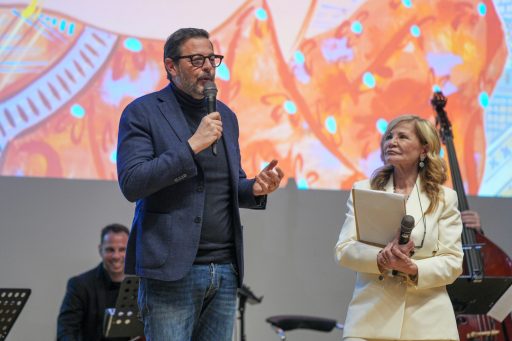 Marco Alparone parla al microfono al suo fianco la presentatrice della serata 