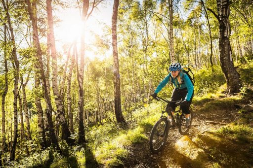 La foto ritrae una giovane donna tra i boschi sul lago di Como in mountain bike. Foto utilizzata per la Lake Como Bike Marathon