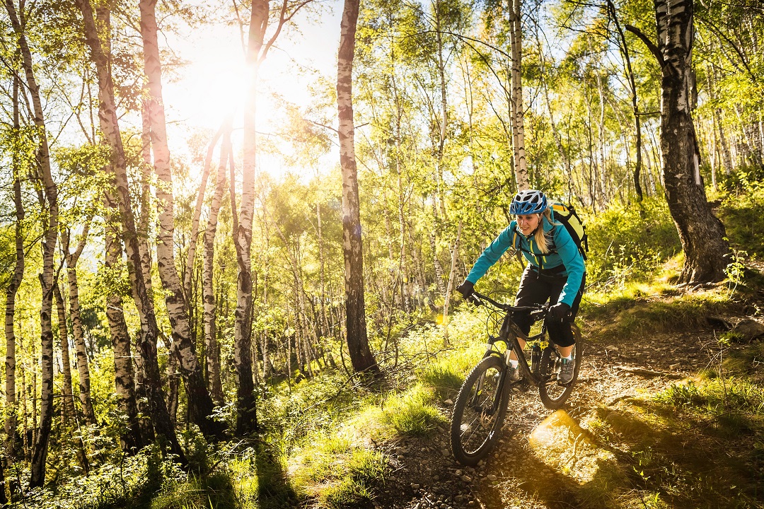 La foto ritrae una giovane donna tra i boschi sul lago di Como in mountain bike. Foto utilizzata per la Lake Como Bike Marathon