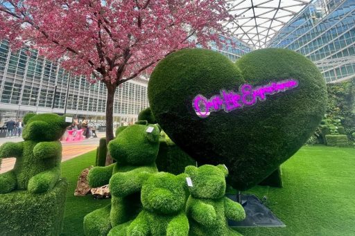 La foto ritrae una delle installazioni di Oasi Life Experience. Sono presenti degli orsacchiotti e un grande cuore ricoperti da un prato curato. Sul cuore c'è scritto con i led 'Oasi Life Experience'. Poi, è presente un albero di ciliegio fiorito