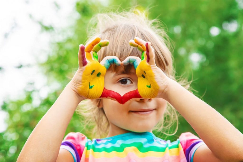 immagine di una bambina che mima un cuore con le mani per simboleggiare inclusione tema chiave della giornata sull'autismo in occasione della quale verrà illuminato palazzo lombardia