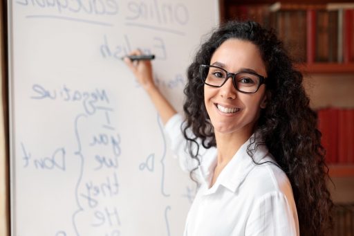 Una giovane insegnante mentre scrive su una lavagna bianca regole di grammatica. Foto utilizzata per l'articolo sul rientro dei giovani talenti dall'estero