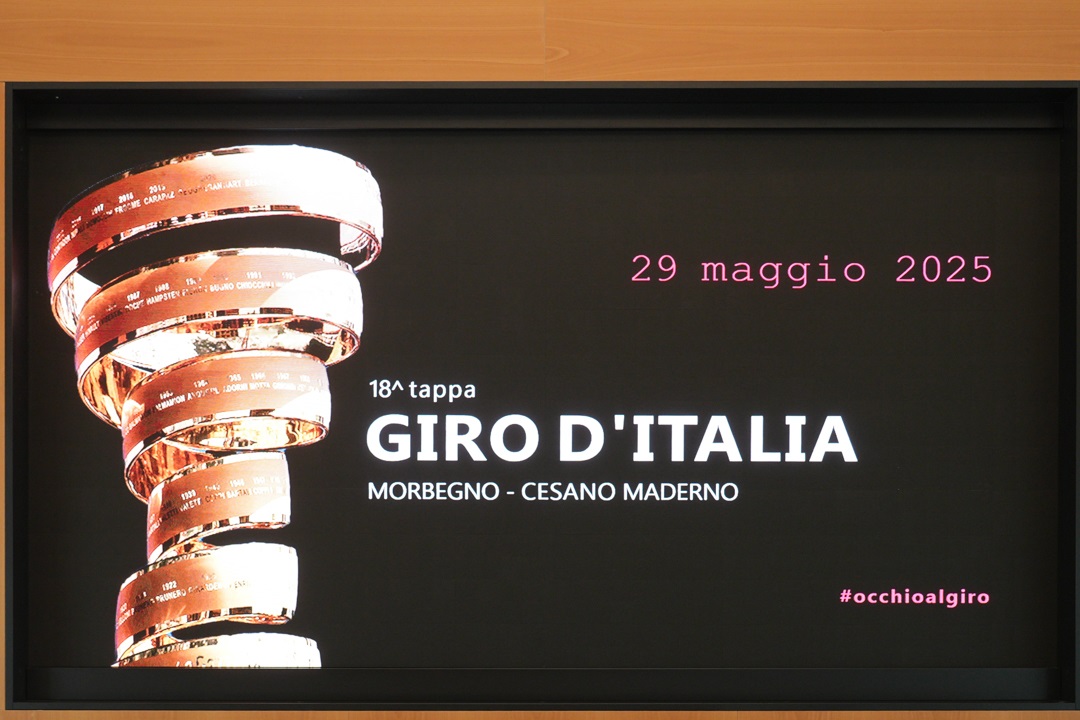 Lo schermo dietro ai relatori della conferenza di presentazione delle tre tappe del Giro d’Italia 2025 in Lombardia con un’immagine del Trofeo Senza Fine 