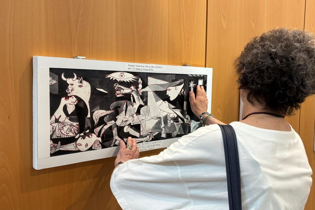 Visitatori che toccano un'opera della mostra inclusiva a Palazzo Lombardia