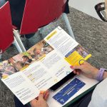 La foto mostra una persona del pubblico dell'evento di premiazione a Goffredo Modena con il pieghevole di Mission Bambini