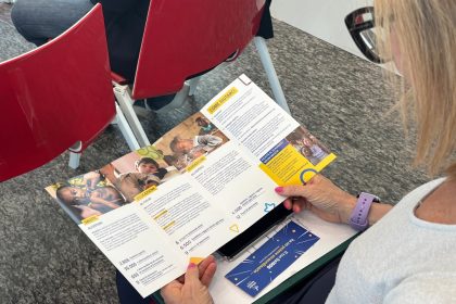 La foto mostra una persona del pubblico dell'evento di premiazione a Goffredo Modena con il pieghevole di Mission Bambini