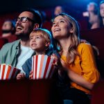 In foto una famiglia al cinema: mamma, papà e figlio guardano un film. Prosegue il sostegno di Regione Lombardia al settore cinematografico