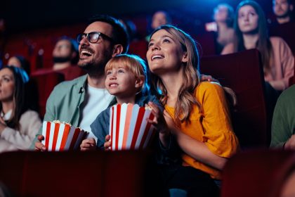 In foto una famiglia al cinema: mamma, papà e figlio guardano un film. Prosegue il sostegno di Regione Lombardia al settore cinematografico