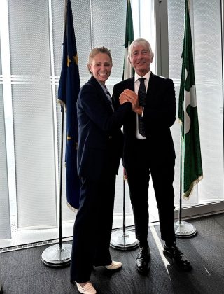 Federica Picchi sottosegretario alla Presidenza della Regione Lombardia stringe la mano al ministro per lo Sport e Giovani Andrea Abodi davanti alle bandiere di Europa, Italia e Lombardia. Tra gli argomenti dell'incontro il ruolo educativo dello sport e la collaborazione tra istituzioni ed enti formativi.
