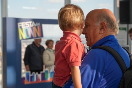 Un nonno con il nipote in braccio durante la festa dei nonni al Belvedere di Palazzo Lombardia