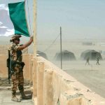 In foto un militare in servizio mentre sventola la bandiera italiana in memoria dei caduti di Nassiriya, onorati da Regione Lombardia con 14 borse di studio alle scuole