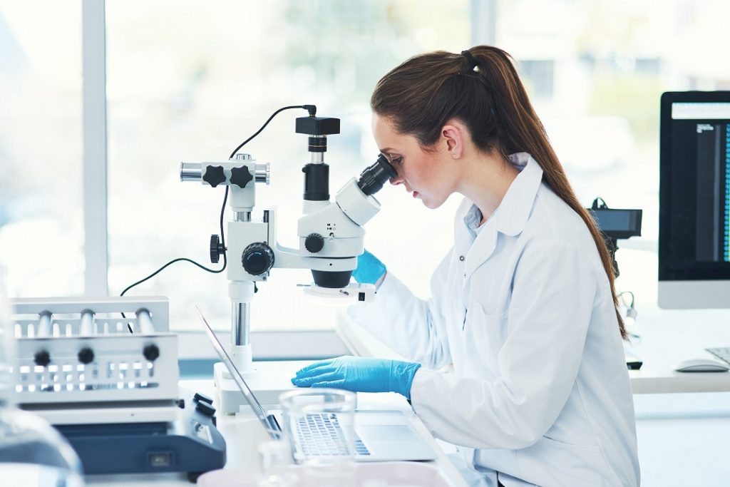 ricercatrice con microscopio per idea del bando infrastrutture di ricerca di regione lombardia per le università