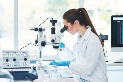 ricercatrice con microscopio per idea del bando infrastrutture di ricerca di regione lombardia per le università