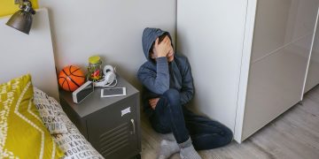 Immagine di un ragazzo seduto per terra con la testa tra le mani per dare idea delle linee guida sul di intervento neuropsichiatrico sul disagio giovanile adottate in Lombardia