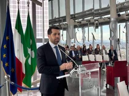 Evento Belvedere miniere turistiche, l'intervento di Clerici. Alle sue spalle le bandiere dell'Ue, dell'Italia e della Lombardia