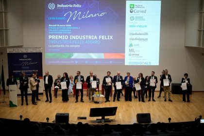 Premio Industria Felix, sul palco sono presenti i premiati che sorreggono un attestato. Alle loro spalle la locandina dell'evento