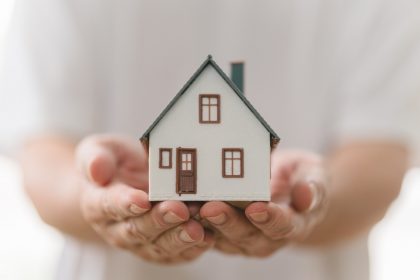 La foto mostra una casa in miniatura tenuta tra due mani. Foto utilizzata in occasione dell'articolo dei nuovi fondi di Regione Lombardia per l'housing sociale