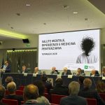 Convegno Associazione Ippocrate La Russa Salute mentale; l'immagine ritrae l'assessore La Russa durante il suo intervento; la visuale permette di vedere la locandina dell'evento trasmessa nel led e gli altri interlocutori seduti al tavolo