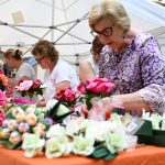 In foto un gruppo di signore dello stand dedicato ai fiori di carta di Monte Isola (Brescia) in posa in piazza Città di Lombardia in occasione della Festa della Regione 2026