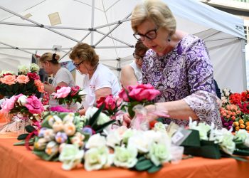 In foto un gruppo di signore dello stand dedicato ai fiori di carta di Monte Isola (Brescia) in posa in piazza Città di Lombardia in occasione della Festa della Regione 2026
