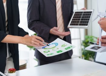 Immagine ritrae due persone in un ambiente lavorativo che hanno tra le mani un grafico e due modellini di pannelli solari