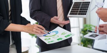 Immagine ritrae due persone in un ambiente lavorativo che hanno tra le mani un grafico e due modellini di pannelli solari