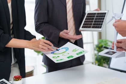 Immagine ritrae due persone in un ambiente lavorativo che hanno tra le mani un grafico e due modellini di pannelli solari