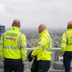 La foto mostra tre operatori di Areu ritratti di spalle mentre guardano la città di Milano. Immagine utilizzata per articolo medici della Lombardia partiti per il venezuela