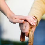 L'immagine ritrae una mano di un'anziano che si sorregge sul bastone e una mano di un'altra persona poggiata sopra. Immagine utilizzata per il Forum sostenibilità sociale che si è tenuto a Palazzo Lombardia