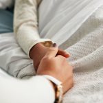 Scaricata da Shutterstock il 24.06.2026 L'immagine mostra una mano di una bambina in un letto di ospedale stretta da un familiare