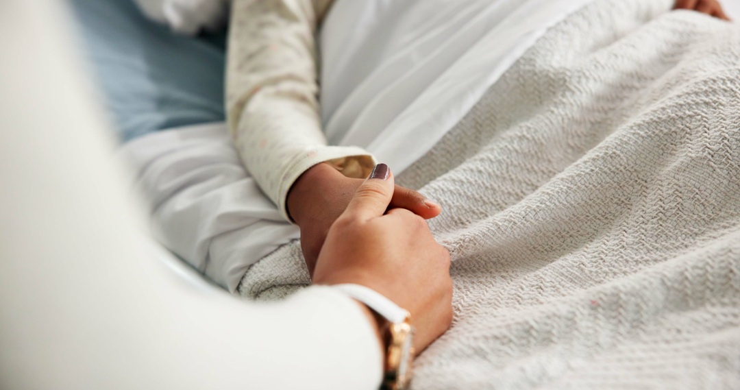 Scaricata da Shutterstock il 24.06.2026 L'immagine mostra una mano di una bambina in un letto di ospedale stretta da un familiare