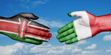 In foto due mani, una con la bandiera dell'Italia e l'altra del Kenya: i due paesi, nello specifico Regione Lombardia, sono coinvolti in un progetto di cooperazione internazionale