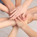 Squadra di volontari che impilano le mani all'interno, immagine scattata dall'alto. Immagine utilizzata per finanziamenti al terzo settore, il runts _Scaricata da Shutterstock il 30.07.26
