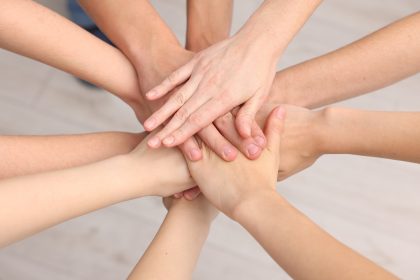 Squadra di volontari che impilano le mani all'interno, immagine scattata dall'alto. Immagine utilizzata per finanziamenti al terzo settore, il runts _Scaricata da Shutterstock il 30.07.26