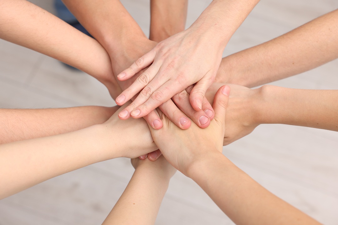 Squadra di volontari che impilano le mani all'interno, immagine scattata dall'alto. Immagine utilizzata per finanziamenti al terzo settore, il runts _Scaricata da Shutterstock il 30.07.26