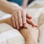 Tema fine vita, immagine utilizzata per silenzio di Regione Lombardia nel caso del lombardo affetto di sclerosi multipla accompagnato alla morte. La foto mostra una mano appoggiata a due mani giunte di una persona che si trova su un letto di ospedale _Shutterstock 26082026