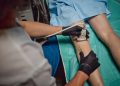 Uomo riceve esame ecografico vascolare sulla parte inferiore della gamba da un medico che indossa guanti in ambiente clinico. Immagine utilizzata per Rete regionale della Chirurgia Vascolare di Regione Lombardia.
