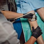 Uomo riceve esame ecografico vascolare sulla parte inferiore della gamba da un medico che indossa guanti in ambiente clinico. Immagine utilizzata per Rete regionale della Chirurgia Vascolare di Regione Lombardia.