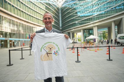 Il sottosegretario Piazza in piazza Città di Lombardia mentre tiene in mano la maglia dell'Unione Italiana Ciechi e Ipovedenti per la Giornata dei cani guida
