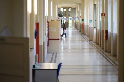 Primo giorno di scuola istituto via Galvani. La foto mostra un corridoio, una maestra e un'alunna che entrano in una classe