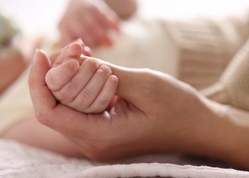 La foto mostra una mano che stringe la manina di un neonato. Foto utilizzata per campagna immunizzazione Regione Lombardia contro il virus respiratorio sinciziale