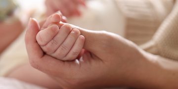 La foto mostra una mano che stringe la manina di un neonato. Foto utilizzata per campagna immunizzazione Regione Lombardia contro il virus respiratorio sinciziale