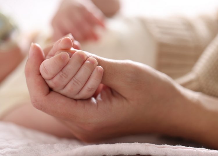 La foto mostra una mano che stringe la manina di un neonato. Foto utilizzata per campagna immunizzazione Regione Lombardia contro il virus respiratorio sinciziale