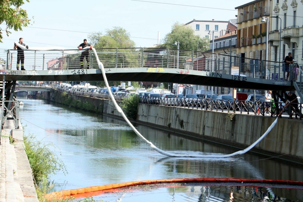 In foto immagini degli operatori in azione per contenere lo sversamento di liquidi nel Naviglio