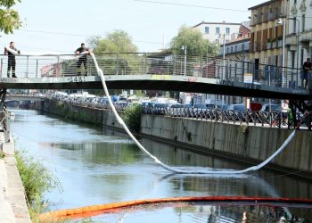 In foto immagini degli operatori in azione per contenere lo sversamento di liquidi nel Naviglio (foto Ansa)
