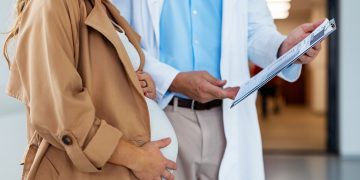 Foto di una donna col pancione e di un medico con una cartella clinica. Immagine utilizzata per articolo parto con analgesia epidurale.